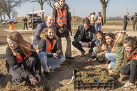 Gedeputeerde Bert Boerman en groep 8 van CBS de Marsweijde helpen mee om plantjes te planten rondom het bijenhotel op de duurzame carpoolplek aan de N34.